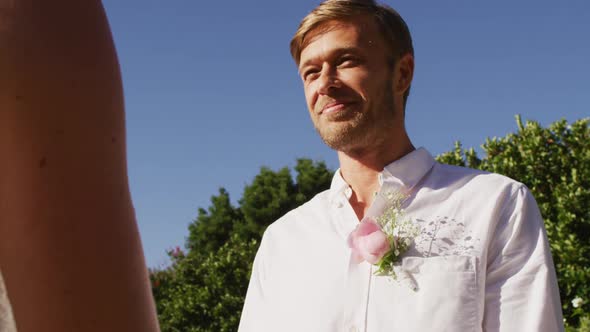 Caucasian bride and groom standing at outdoor altar with wedding officiant during ceremony