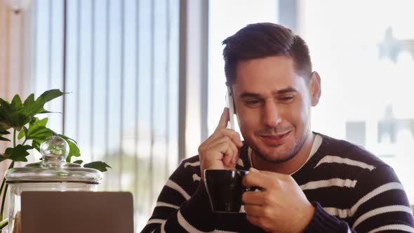 Man talking on mobile phone while having coffee