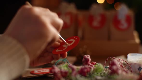 Closeup Tracking Shot of Unrecognizable Man Writing Number on Red Bag By Brush and White Paint on