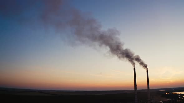 Factory with pipes among nature in the evening. 