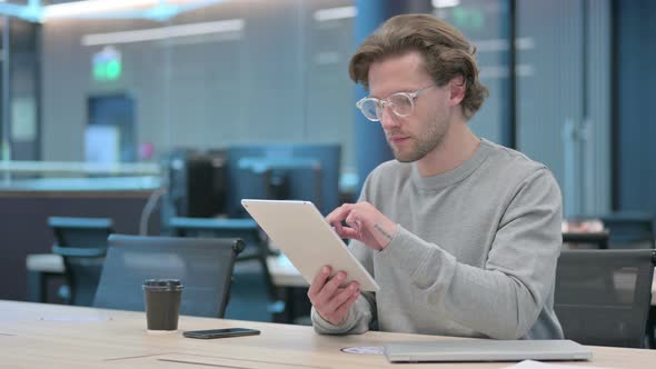 Attractive Young Businessman Using Tablet in Office