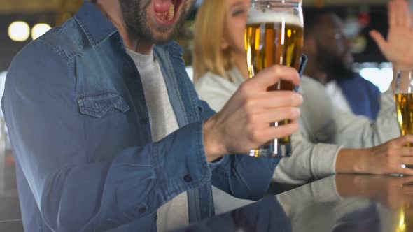 Young People Clinking Beer in Bar, Celebrating Favorite Sports Team Victory