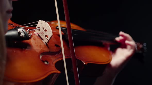 A Woman Musician Plays a Brown Violin and Runs a Bow Along the Strings