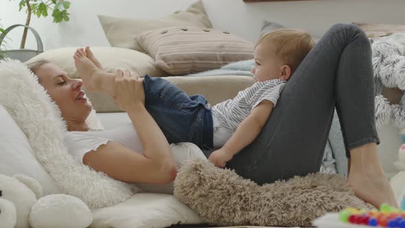 happy and smiling mom cuddles her son child baby playing with him