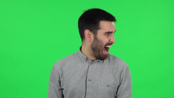 Portrait of Brunette Guy Is Very Angry and Screaming. Green Screen