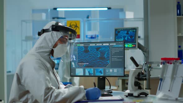 Scientist in Protection Suit Typing on Pc Working in Medical Laboratory
