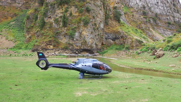 Helicopter Taking Off Over Field and River with Passengers in the Highlands