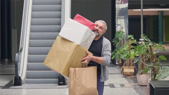 Happy Man With Shopping Bags and Presents For Christmas Walking Out From the Mall