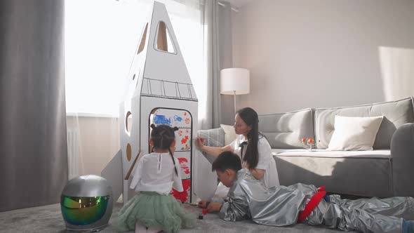An Asian Female with Kids Play in the Living Room at Home a Boy in an Astronaut Costume Sitting on