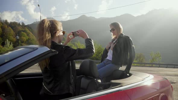 Beautiful Girls Take Photos on a Smartphone Inside a Red Convertible