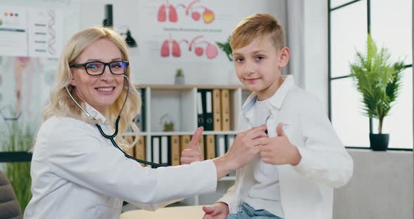 Female Doctor Checking Teen Boy's Lungs and They Together Gesturing Good Work into Camera
