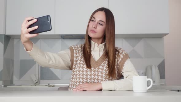 The Girl Poses on the Phone Camera Takes a Selfie
