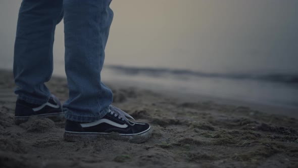 Man Legs in Sneakers Standing on Sea Shore