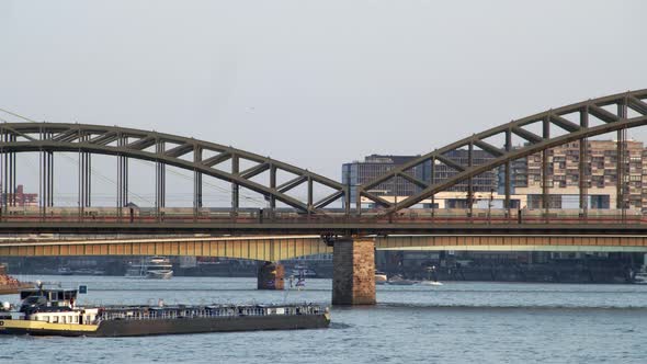 An oil gas tanker passes under the Hohenzollern Bridge in Cologne. Above it, an ICE high-speed train