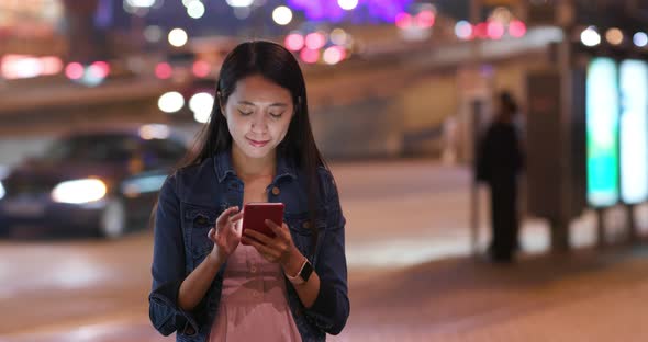 Young woman check on mobile phone in city at night