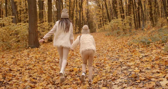 Mother Walking with Preteen Daughter in Autumn Park