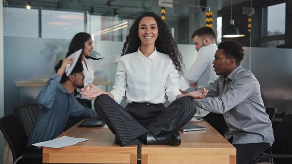 Young Girl Meditate in Lotus Position Sitting on Table in Office Multinational Colleagues Quarreling