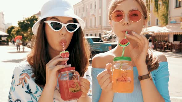 Two young beautiful smiling hipster girls in trendy summer clothes and panama hat