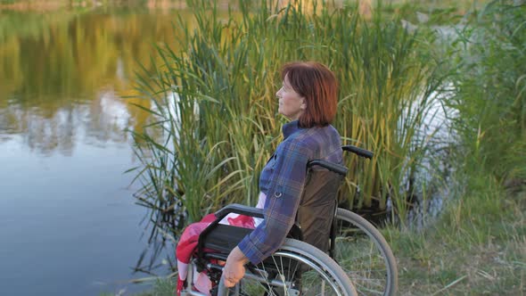 Mature Woman Sit on Wheelchair Near Lake