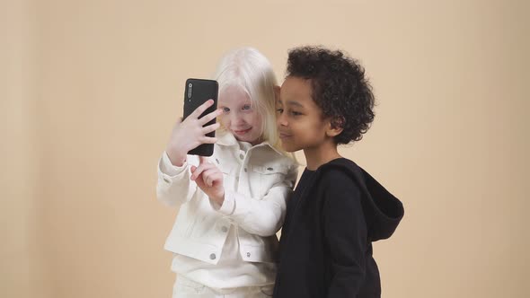 Funny Children with Diverse Appearance Pose i Studio with a Smartphone in Hands