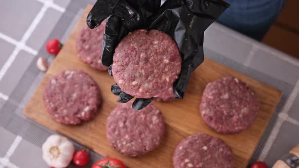 Woman Chef in Black Gloves Prepares Cutlets at Domestic Kitchen on a Wooden Cutting Board