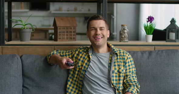 Young Man Is Watching TV, Laughing at TV Program