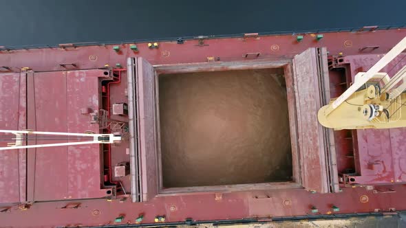Crane loading sand into cargo ship