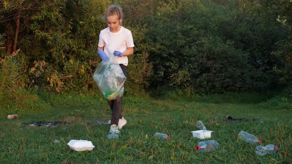 Girl in Gloves Picks Up Trash After a Picnic in the Woods