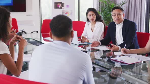 Senior businessman discussing with young business people in meeting room in modern office