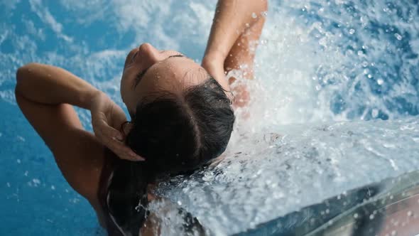 Close-up Young Woman Getting Hydrotherapy in the Pool of a Spa Hotel. Beautiful Girl Relaxing with