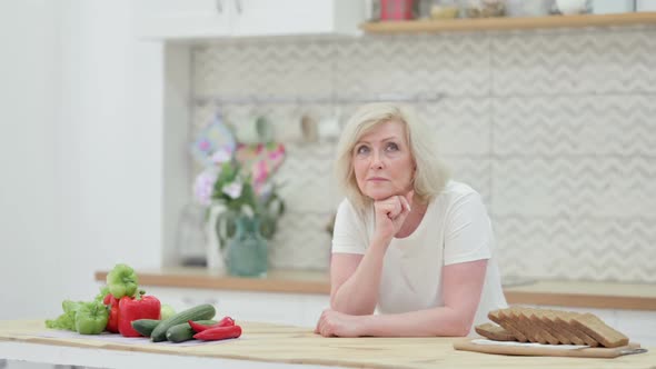 Worried Old Woman Thinking While Standing in Kitchen