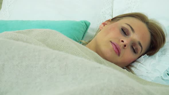 A Young Attractive Woman Sleeps in a Bed