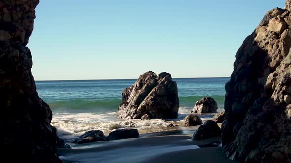 SLOWMO waves crashing against rocks jutting out in Malibu, California