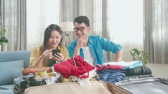 Asian Couple Plan For Trip By Mobile Phone On The Sofa At Home