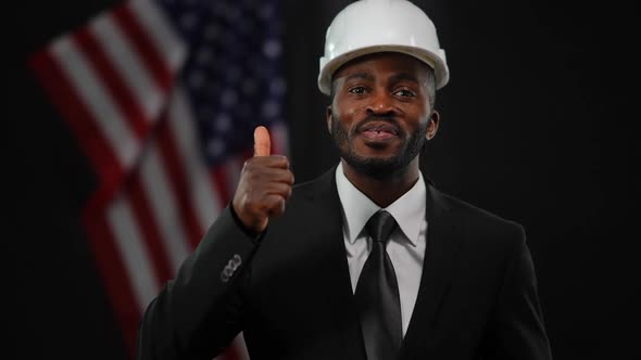 Cheerful Handsome African American Man in Formal Suit and Hard Hat Presenting Real Estate