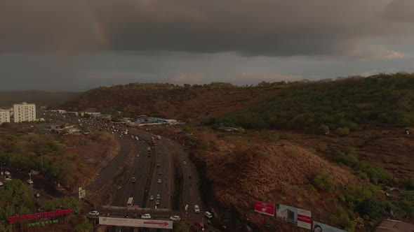 Flying over a busy highway on a rainy day under a rainbow.