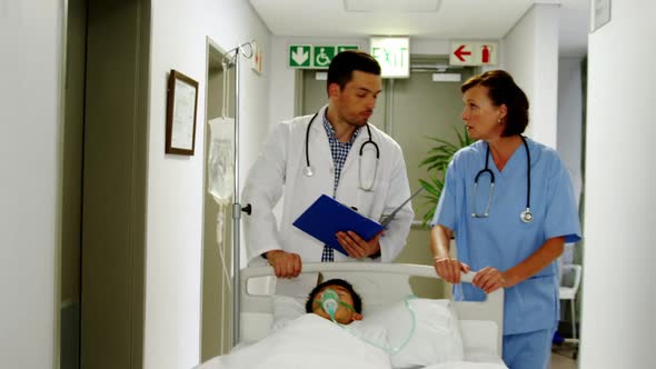 Doctors discussing over medical report while rushing a patient on emergency room