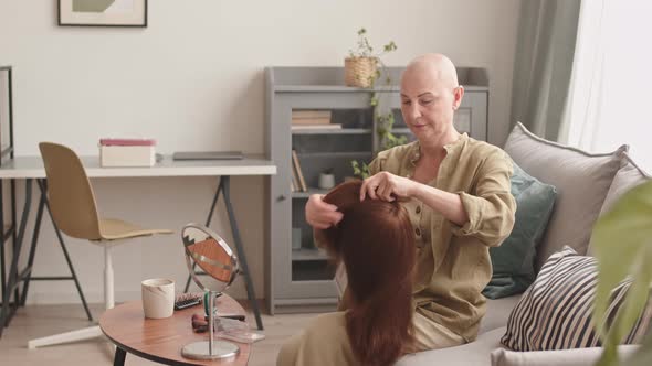 Hairless Woman Putting on Wig at Home