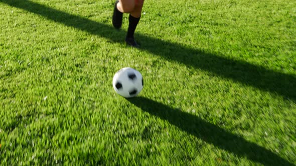 A soccer player on offense running with a football dribbling up the field to score a goal and win th