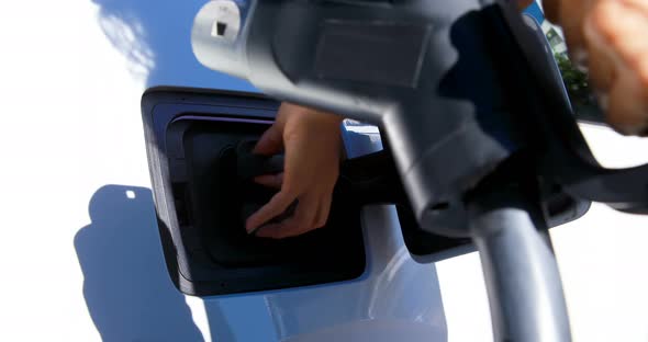 Woman charging electric car at charging station