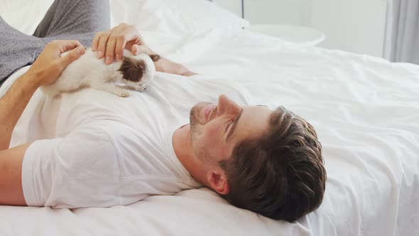 Happy young man lying on bed stroking his puppy 4K 4k