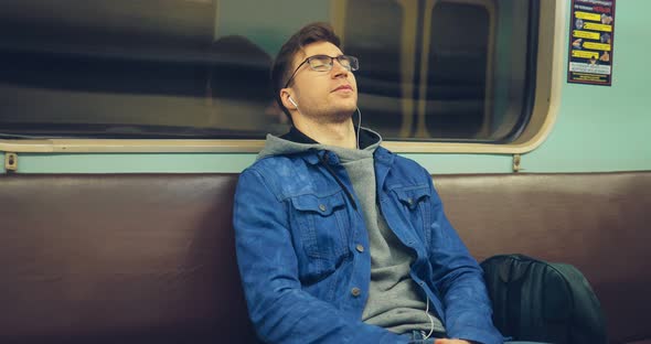 Handsome Guy with Glasses is Riding in an Empty Car Listening to Music with Headphones with Eyes