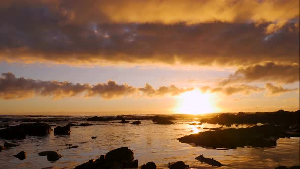 TimeLapse - Beautiful golden sunset with clouds aglow over ocean anding across quickly