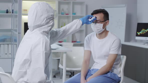 Unrecognizable Doctor in Hazmat Suit Measuring Patients Temperature