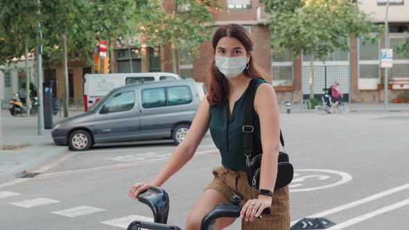 Young Woman Sport Activity In Medical Mask Rides Rent Ciry Bicycle in City Center After Quarantine