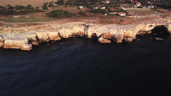 Drone top down aerial view of waves splash against rocky seashore, background. Flight over high clif