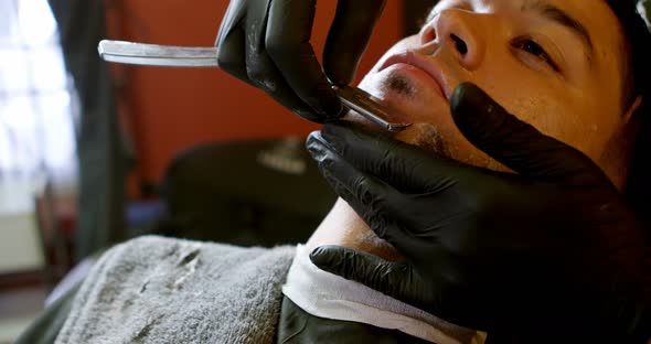 Man getting his beard shaved with straight razor 4k