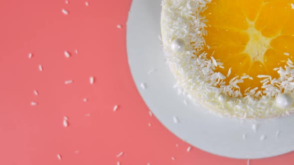 Cake with Orange and Coconut Shavings Spun on a Pink Background