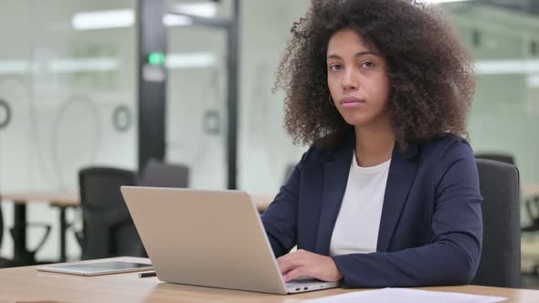 Young African Businesswoman with Laptop Looking at Camera