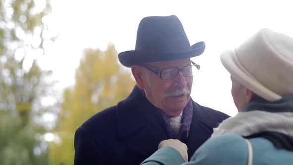 Concept of old age, retirement and people - happy senior couple walking in autumn city park